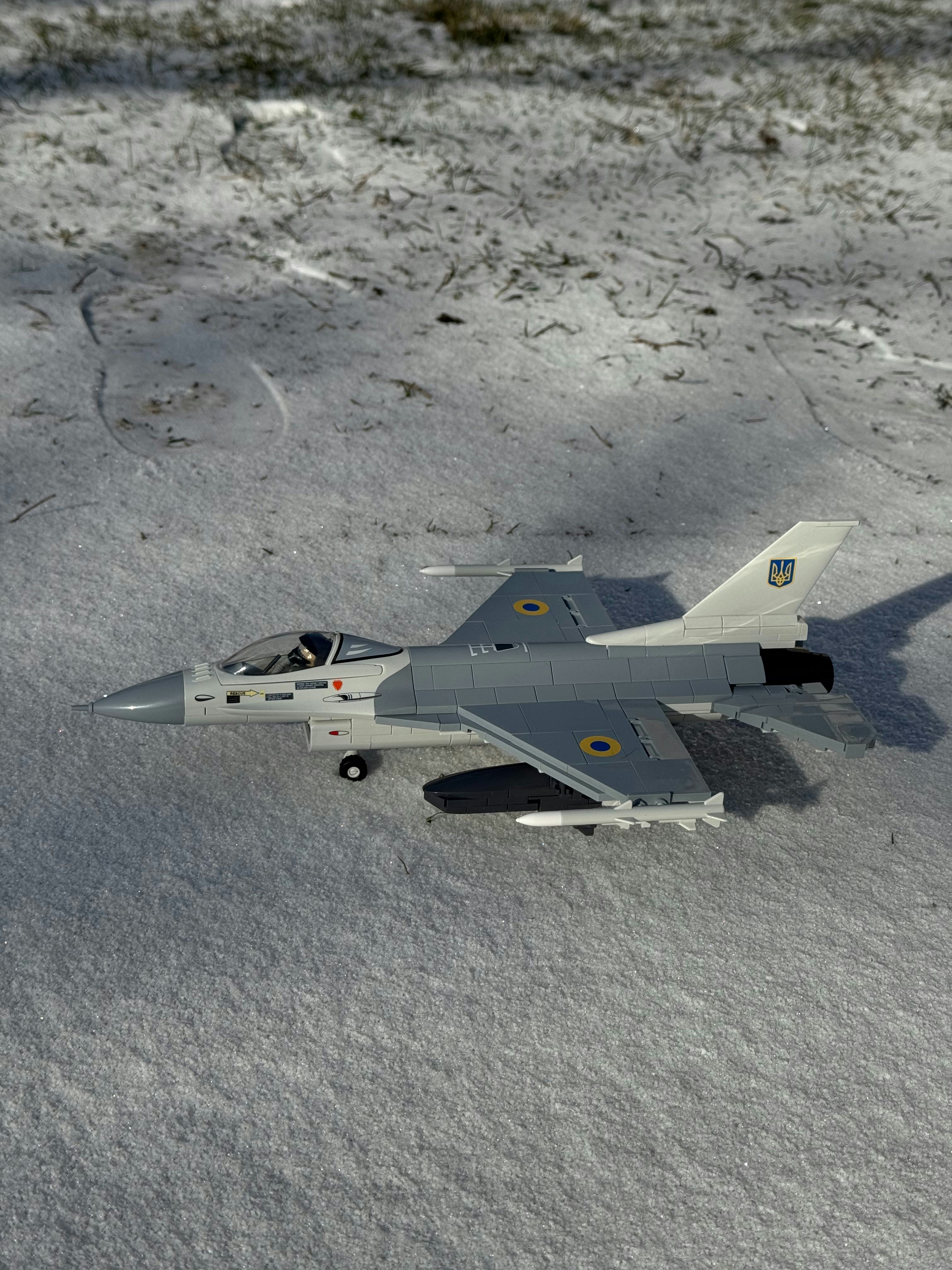 A toy airplane rests on a snowy surface.