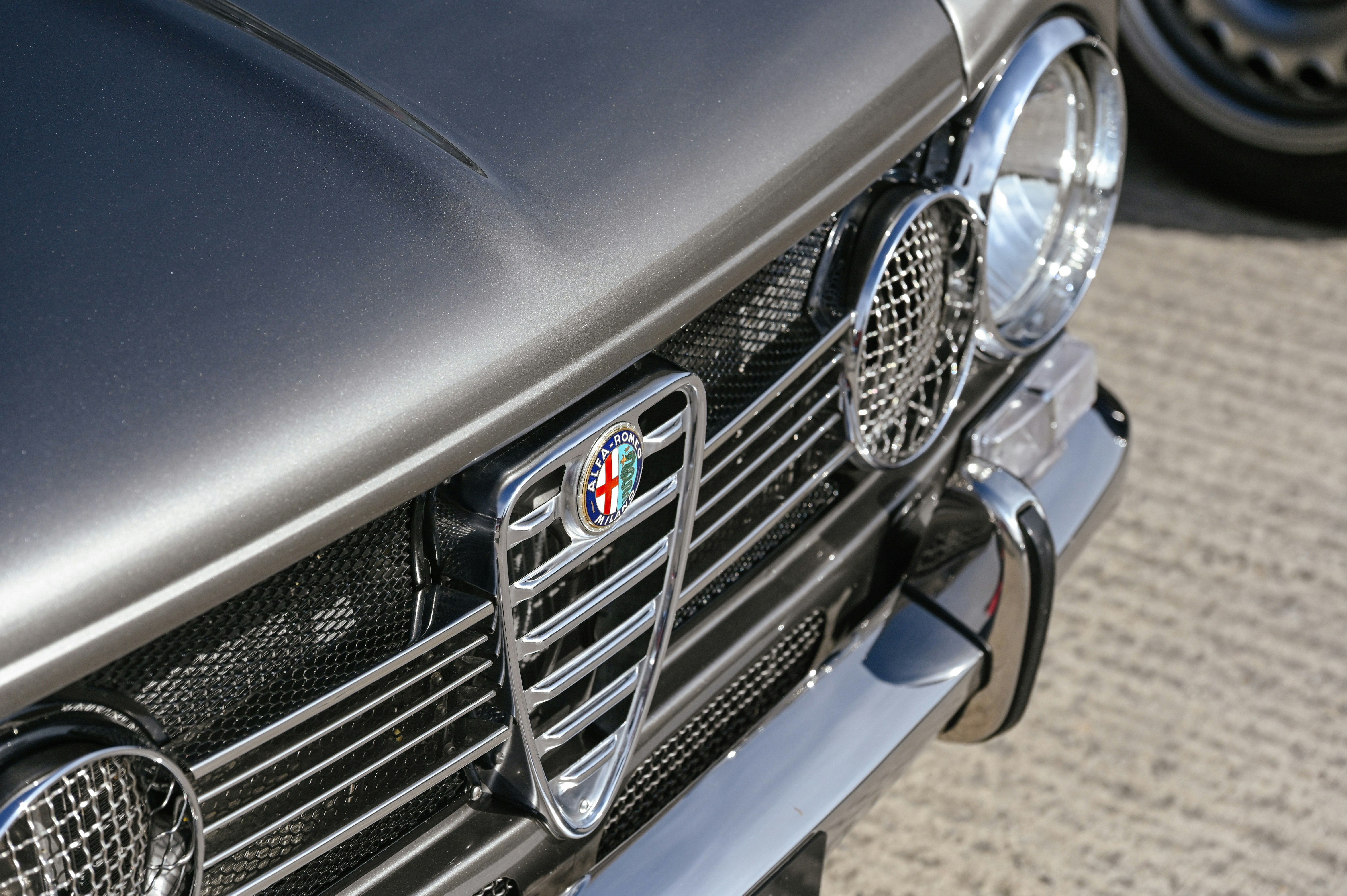 Vordere Kühlergrill und Scheinwerfer eines alten grauen Autos.