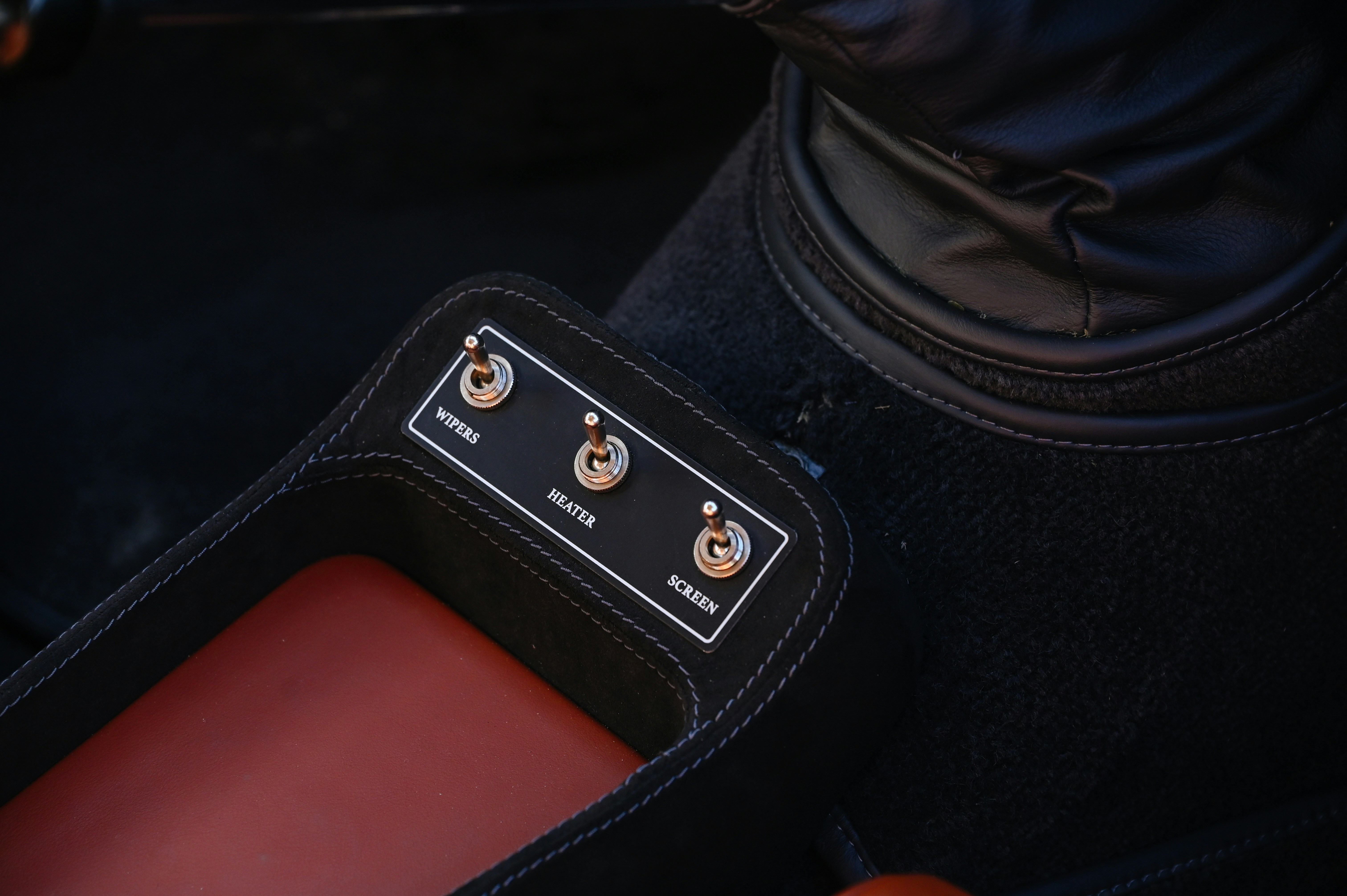 A car's interior has three toggle switches.