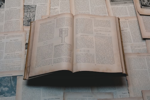 An open book surrounded by loose pages.
