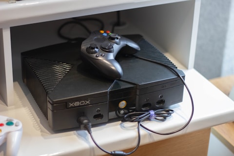 Here's a caption: an original xbox console with a controller.