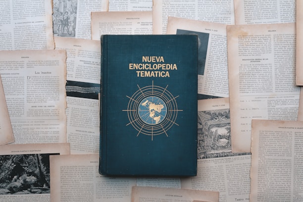 An encyclopedia lies surrounded by scattered papers.