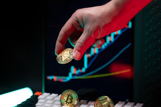 Hand holding ethereum with crypto graphs in background.