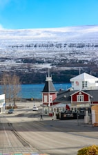 Red building by a road with snowy mountains.