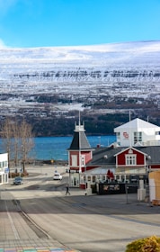 Red building by a road with snowy mountains.