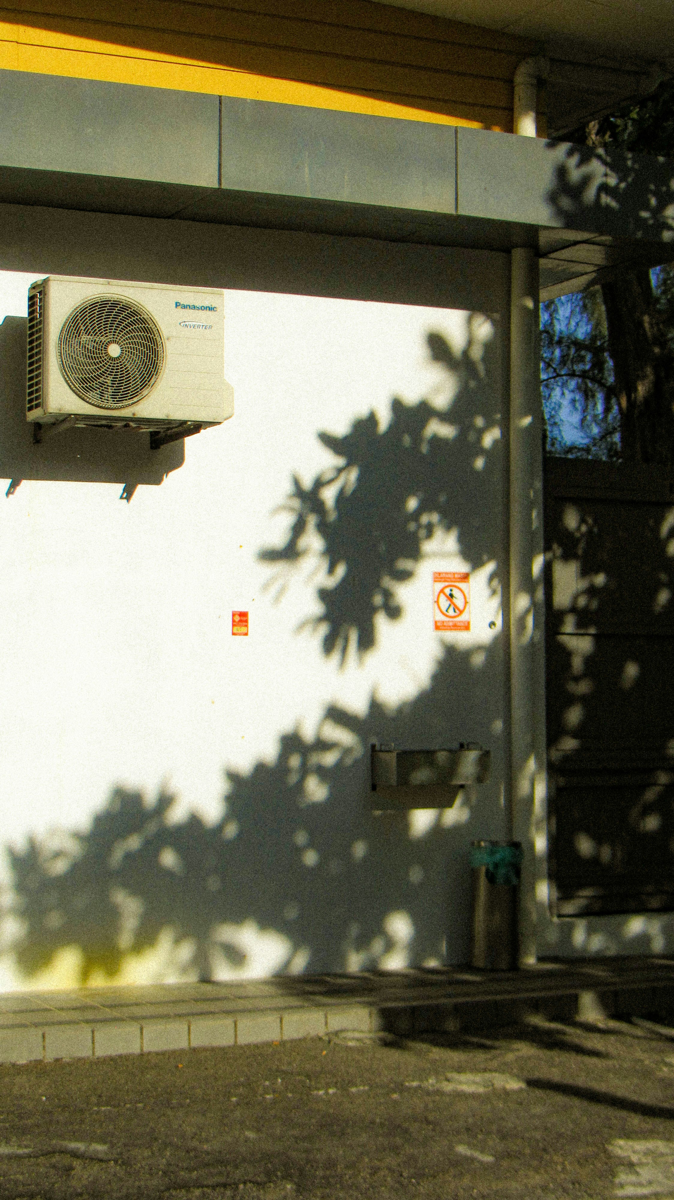 Shadows cast on a building with an ac unit.