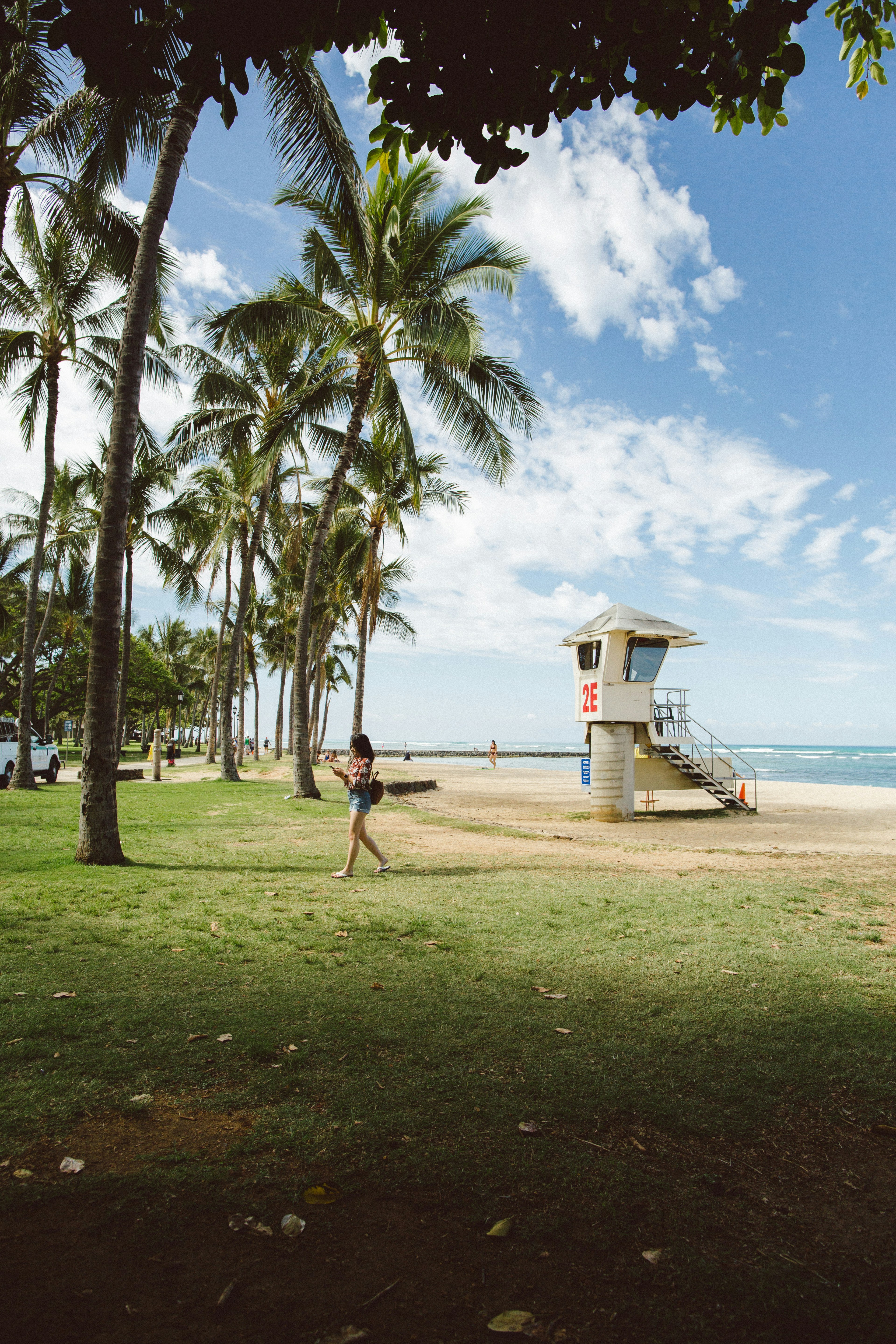 Woman walks past a tropical beach and lifeguard stand.