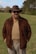 A man in a brown hat stands outdoors.