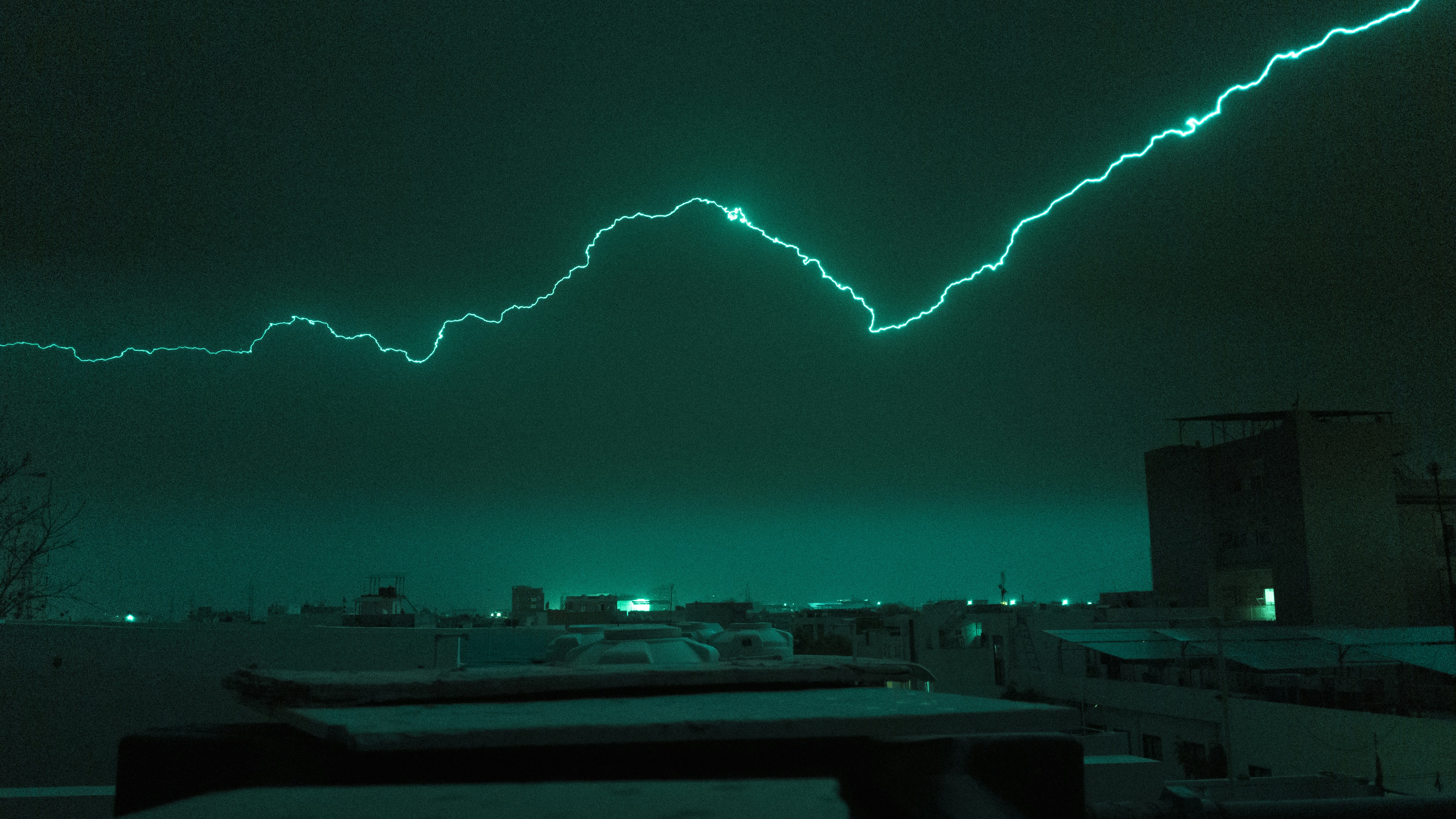 Lightning strikes across a dark, urban skyline.