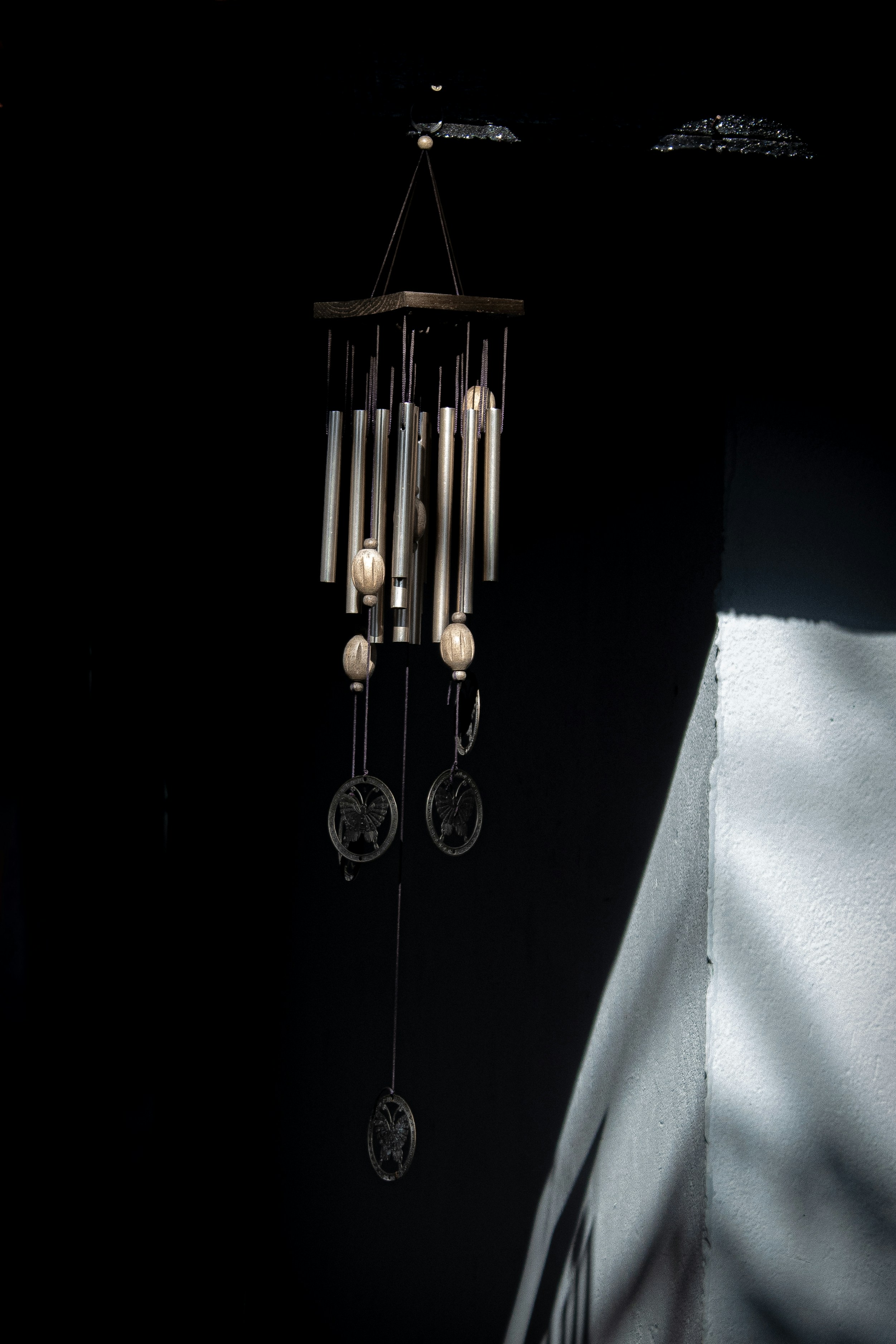 Wind chimes hang against a stark black background.