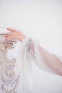 Elegant hand rests against a decorative white surface.