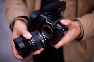 Hands hold a camera with a lens.