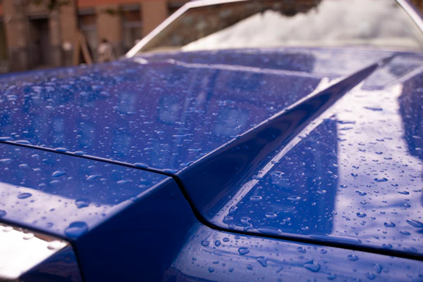 Water beading on a glossy blue car hood