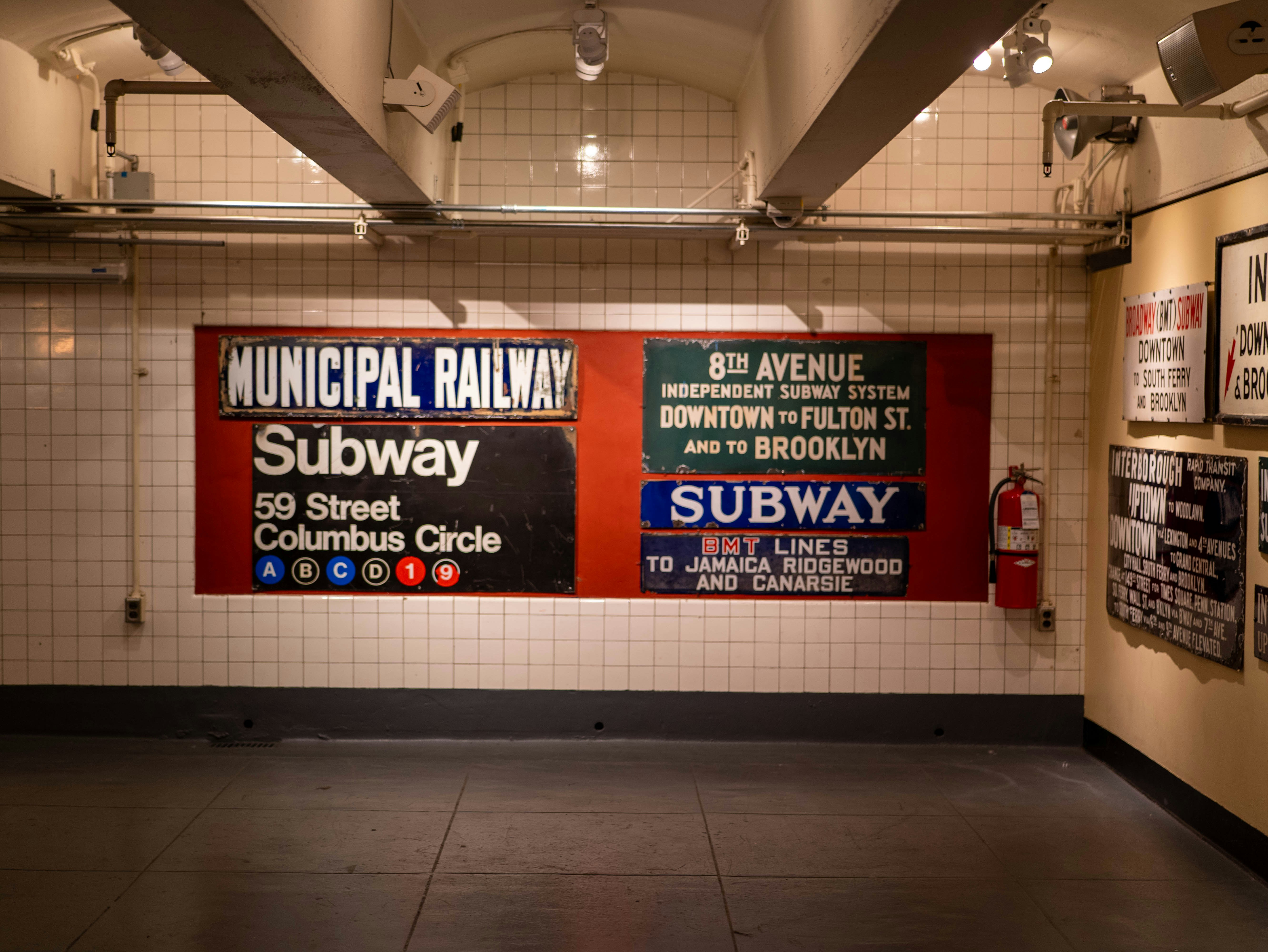 Old subway signs are mounted on a wall.