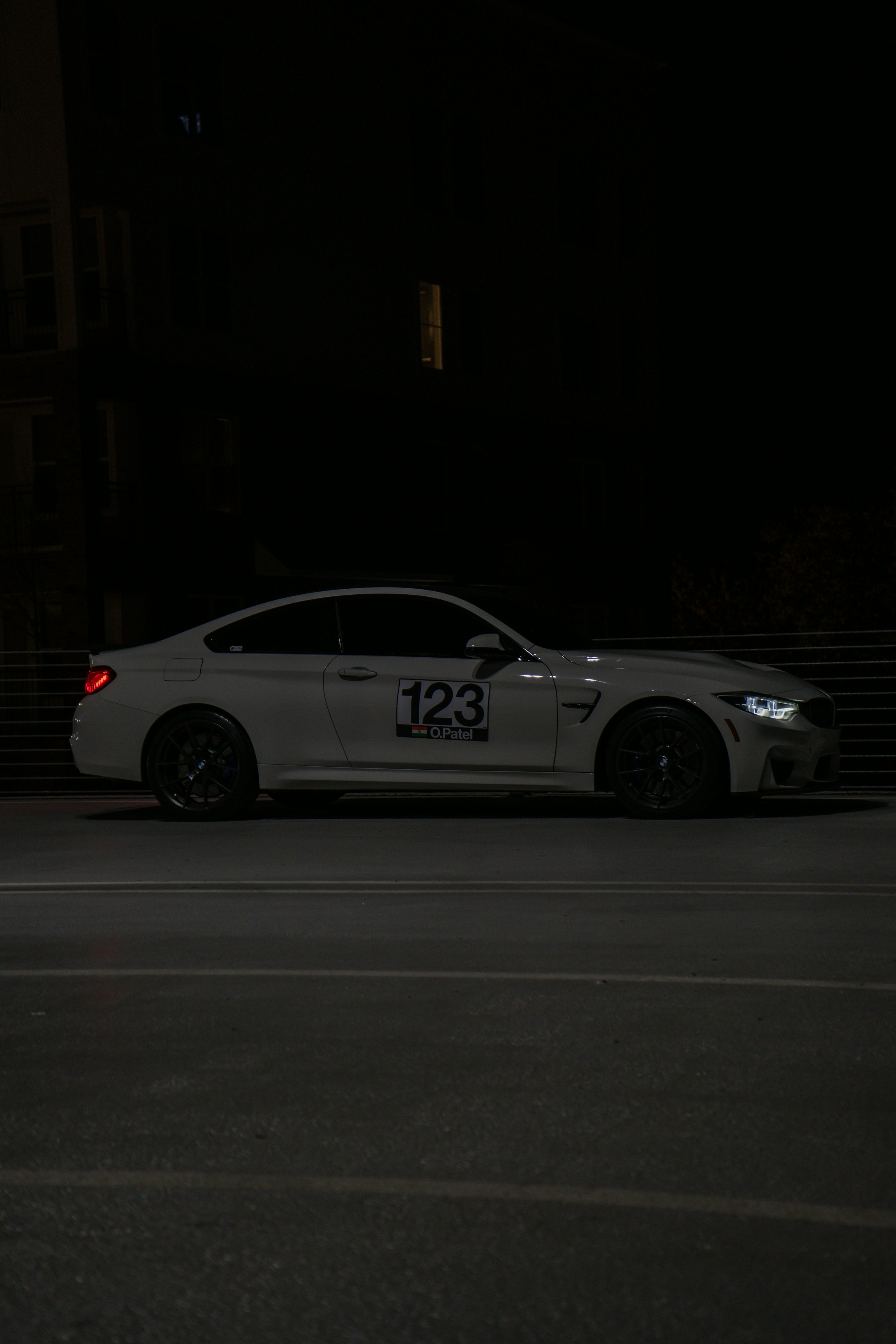 A white BMW m4 is parked at night.
