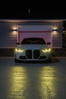 A white BMW car parked in front of a garage.
