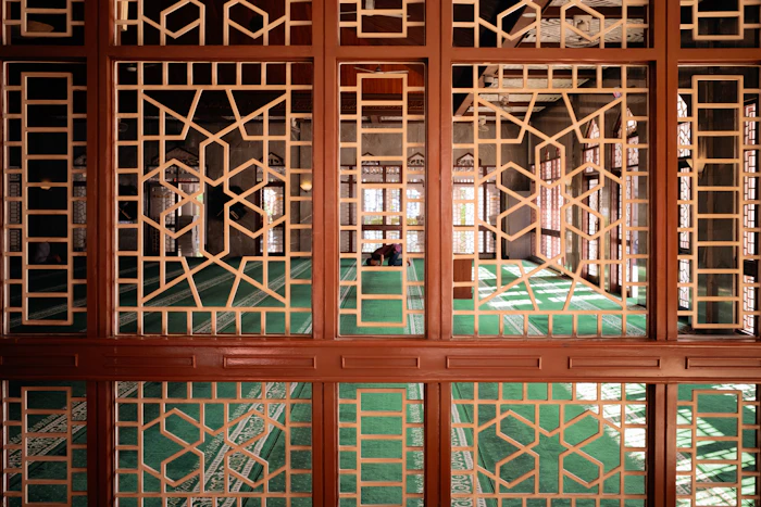 Ornate mosque interior with intricate wooden screens and arches.