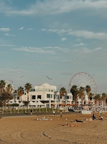 Beach scene with people, ferris wheel, and blue sky.