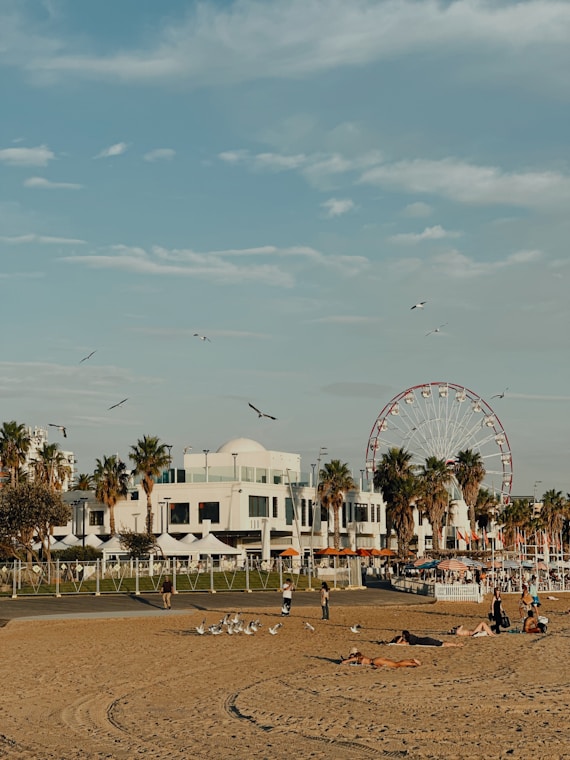 Beach scene with people, ferris wheel, and blue sky.