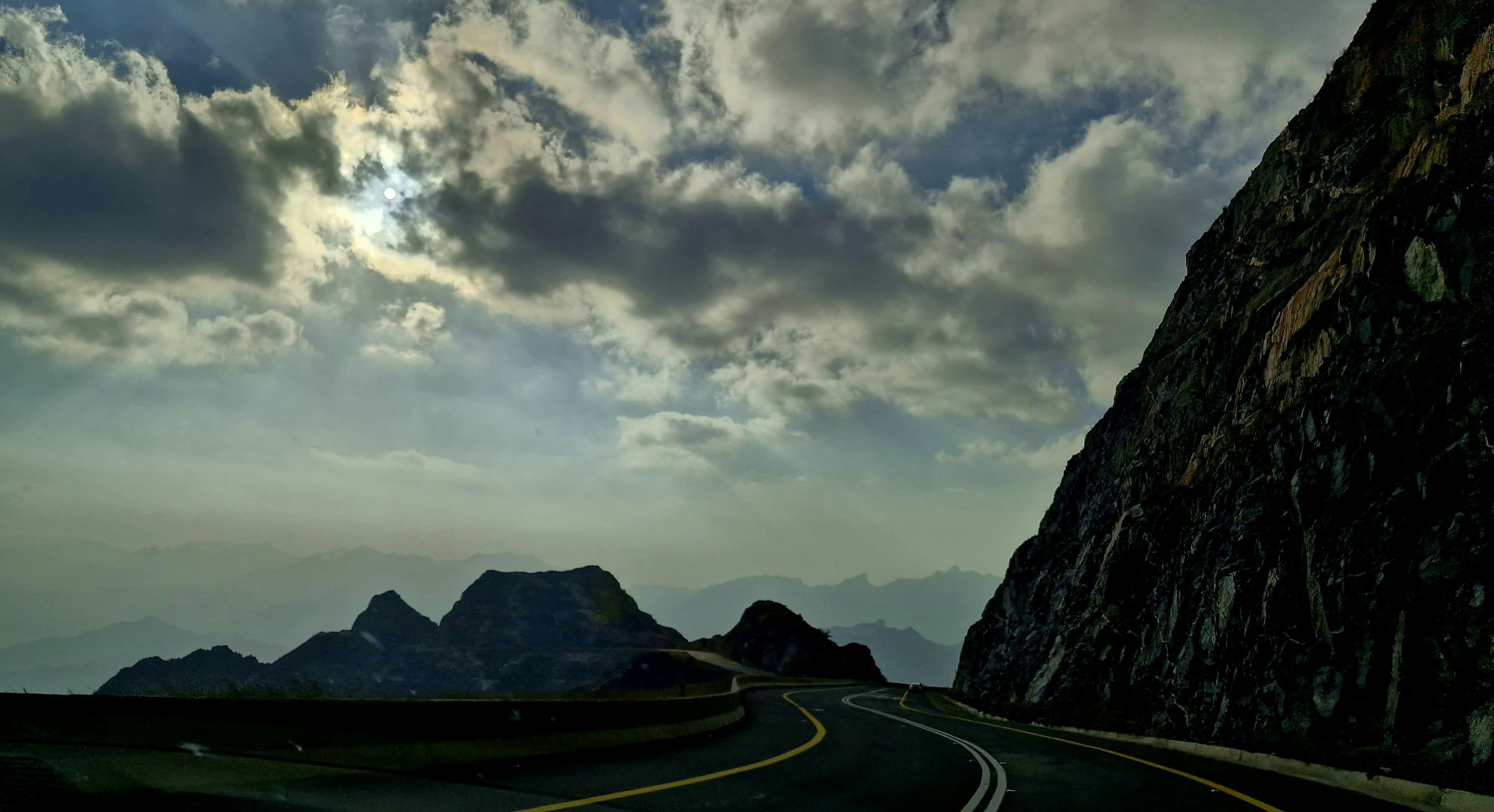 A winding road leads through mountains and clouds.