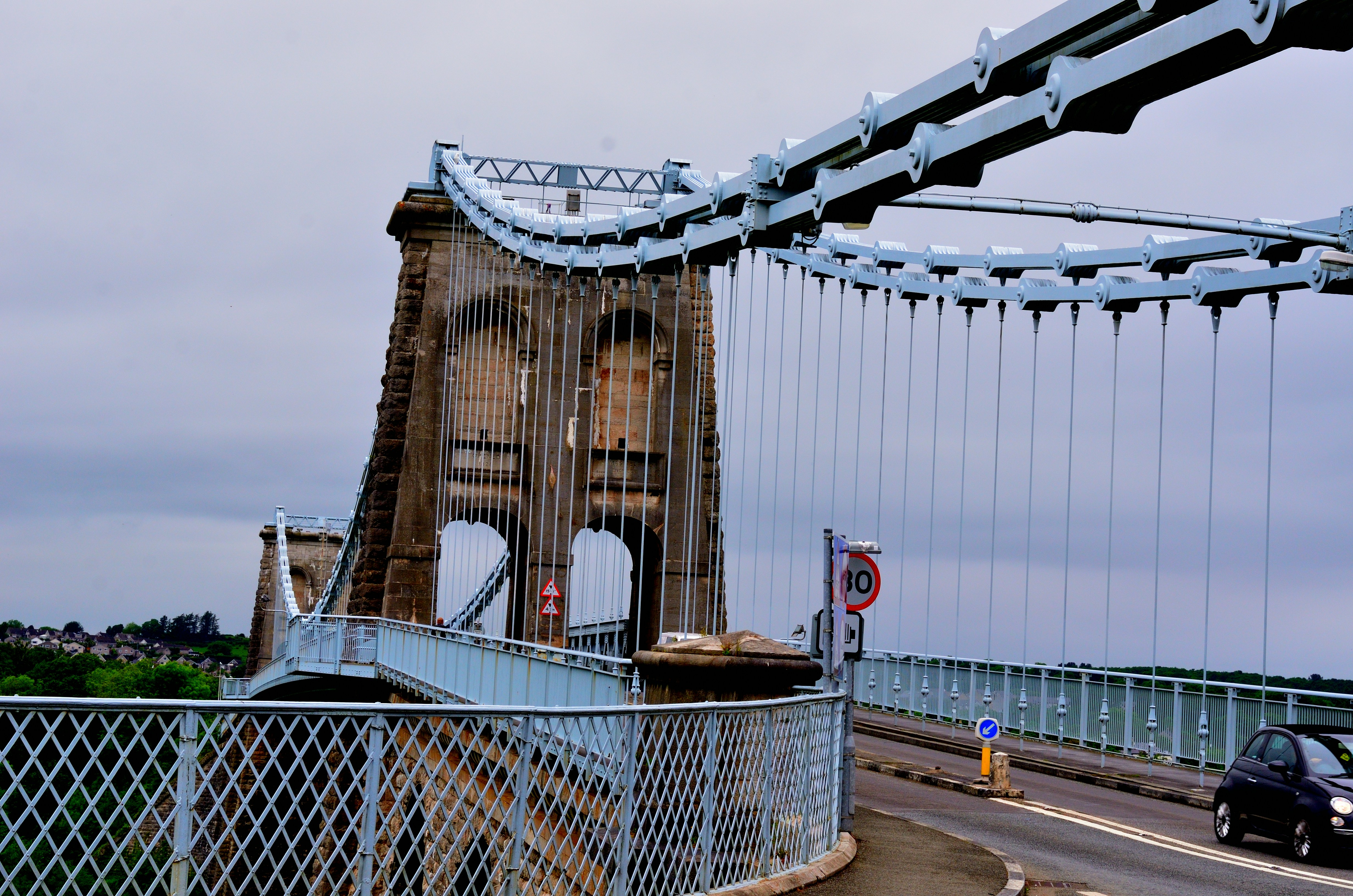 A bridge spans a road on a cloudy day.