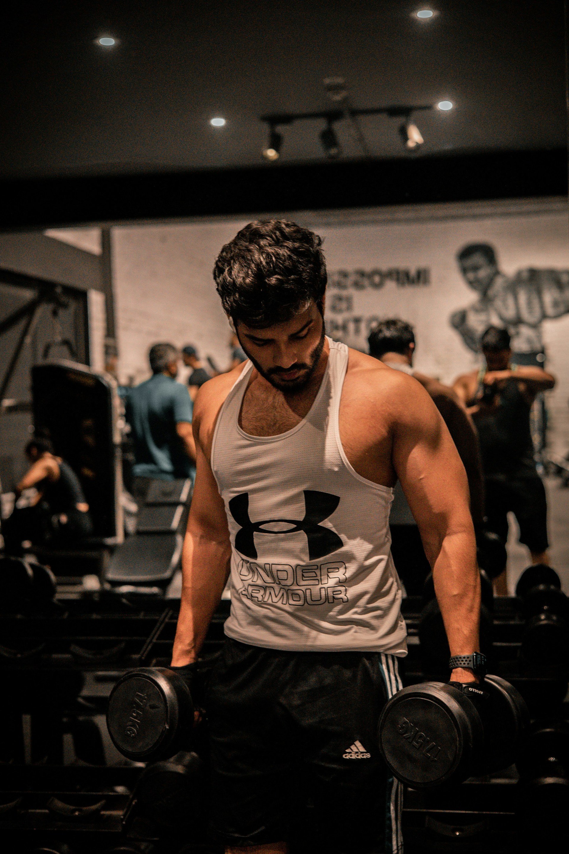 A muscular man lifts dumbbells at the gym.