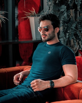 A man is stylishly posing on a couch.