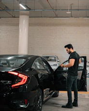 A man is vacuuming the car's interior.