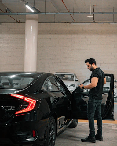 A man is vacuuming the car's interior.
