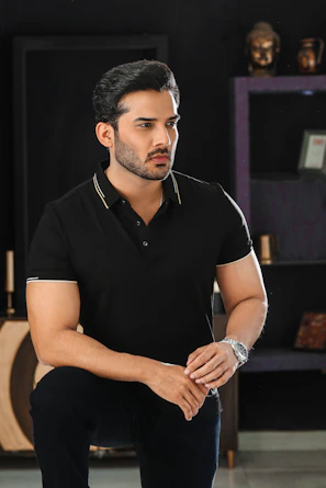 A man poses in a black shirt.