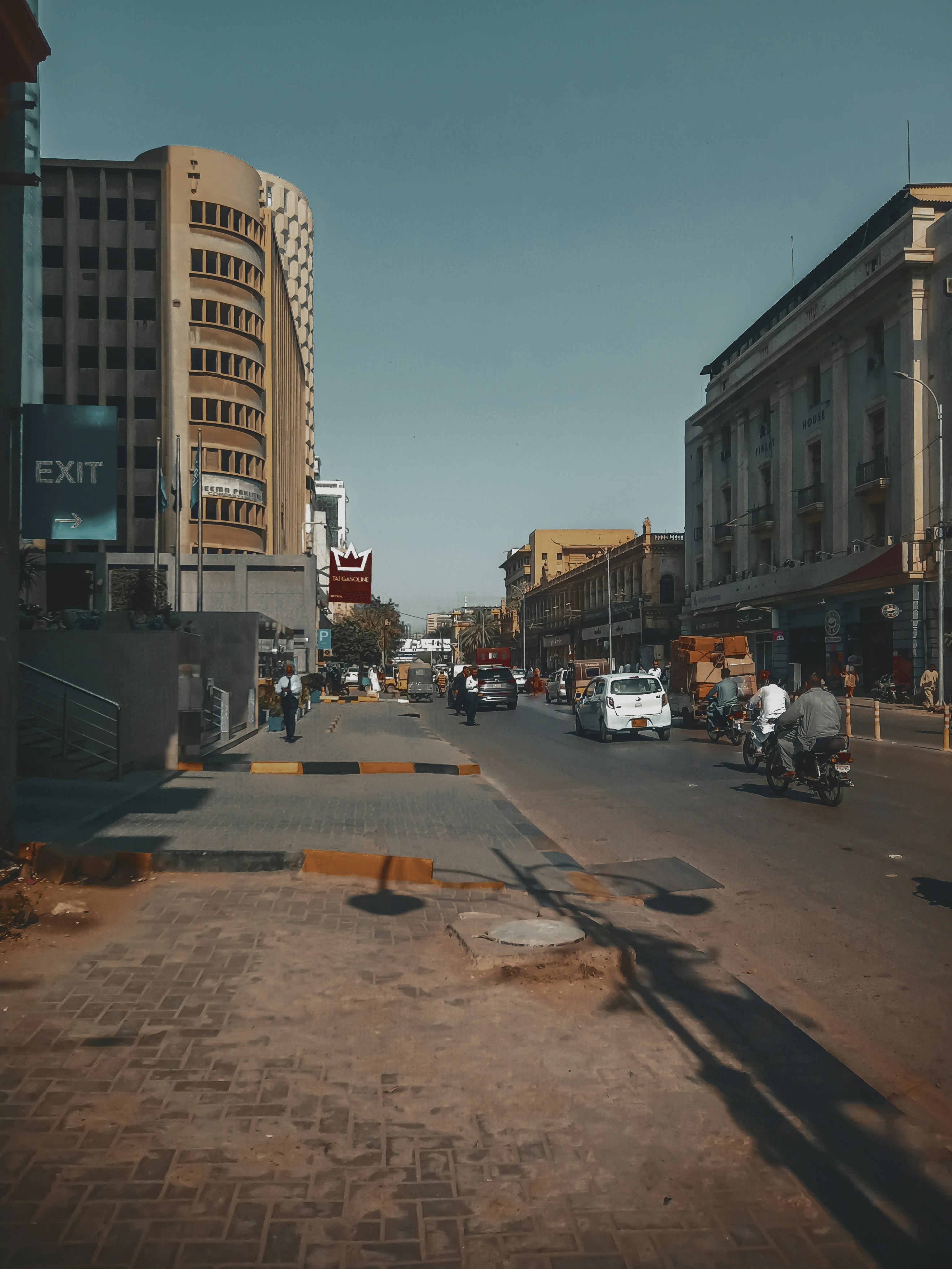 A sunny street scene with buildings and vehicles.