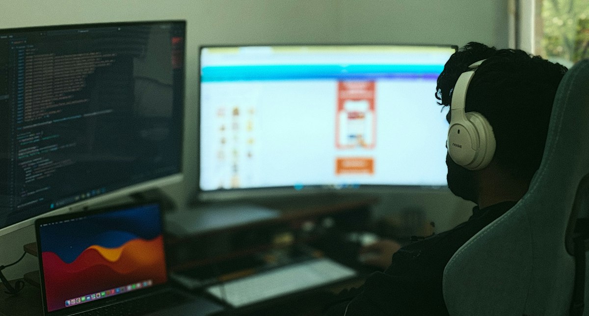 Analista trabalhando em múltiplos monitores e dashboards