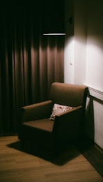 A lit armchair is sitting in a darkened corner.