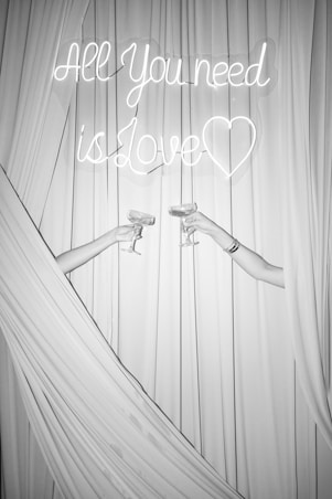 Two people toast with champagne and a love sign.