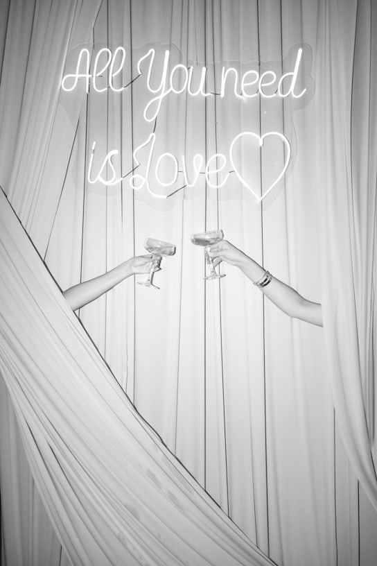 Two people toast with champagne and a love sign.