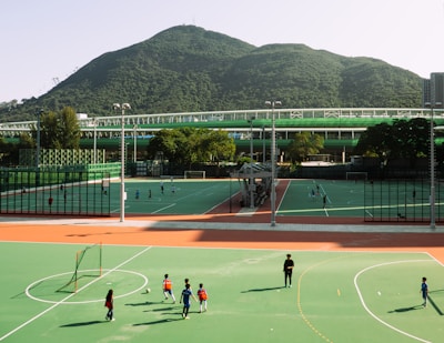 Children play soccer on a field with mountains.