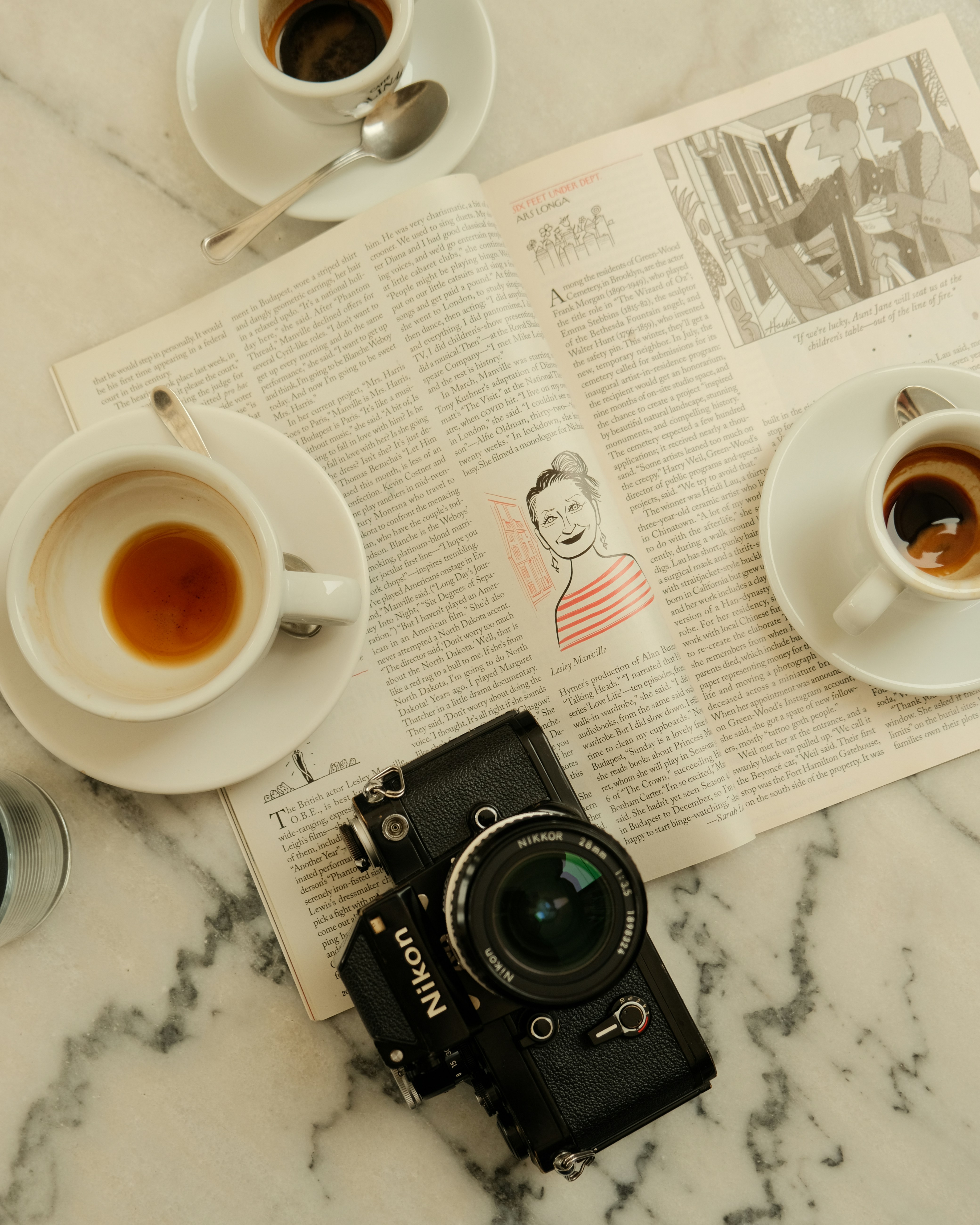 테이블 위에 놓인 에스프레소, 신문, 그리고 카메라