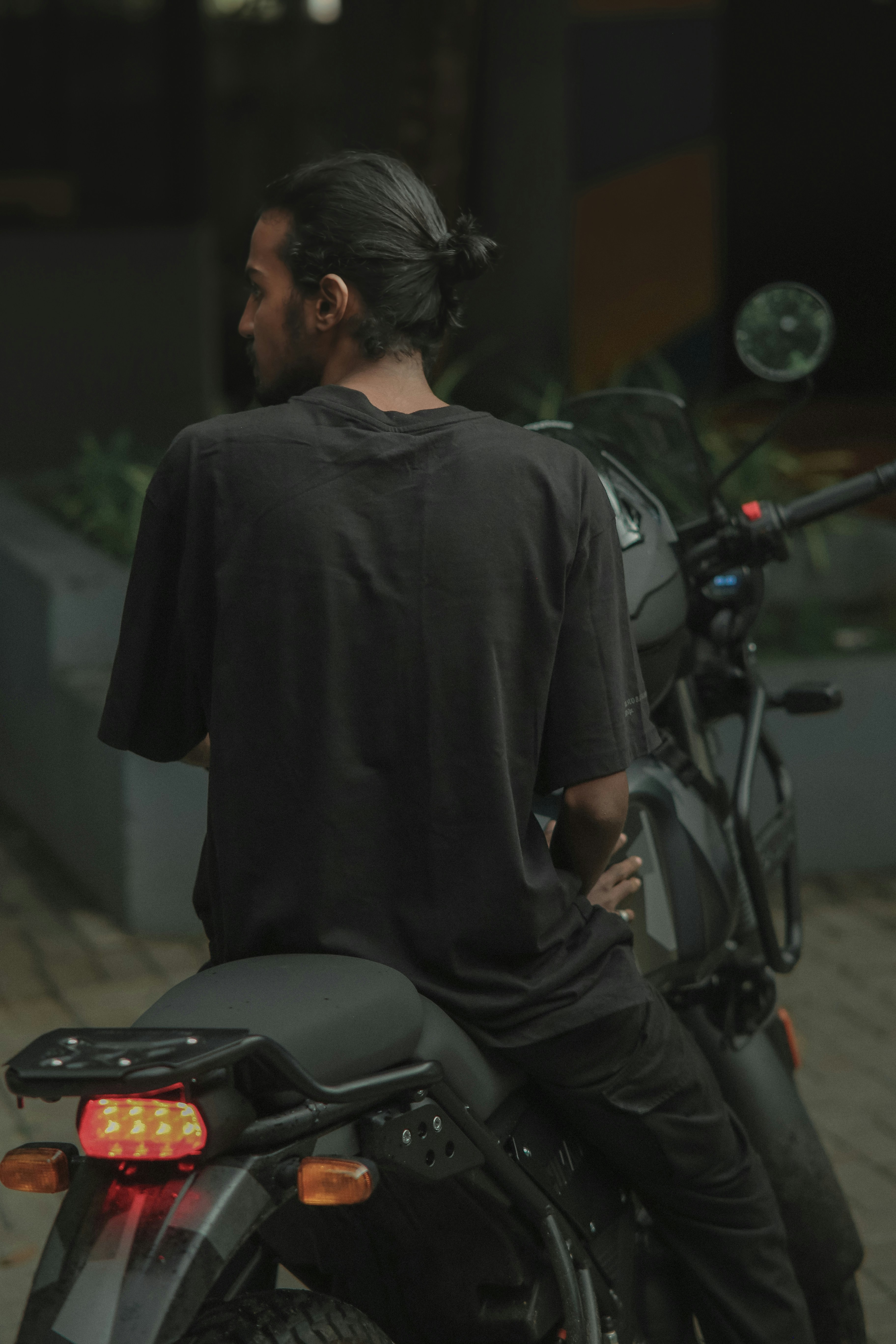Man sits on a motorcycle, looking away.
