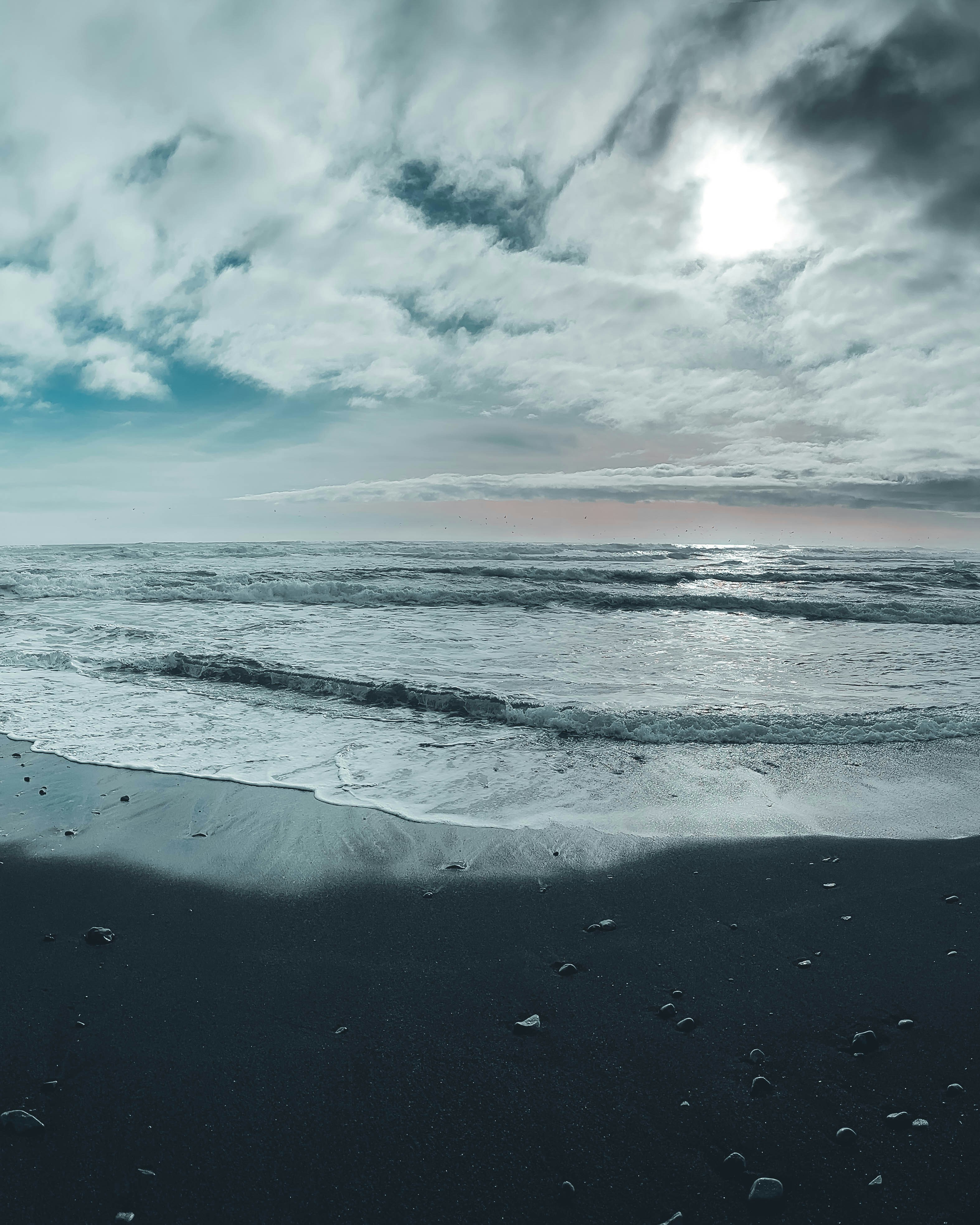 Las olas del mar rompen en una playa oscura y arenosa.