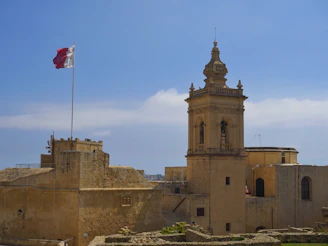 A castle flies a flag under a bright sky.