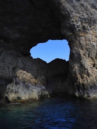 Cave opening frames the bright blue sky.