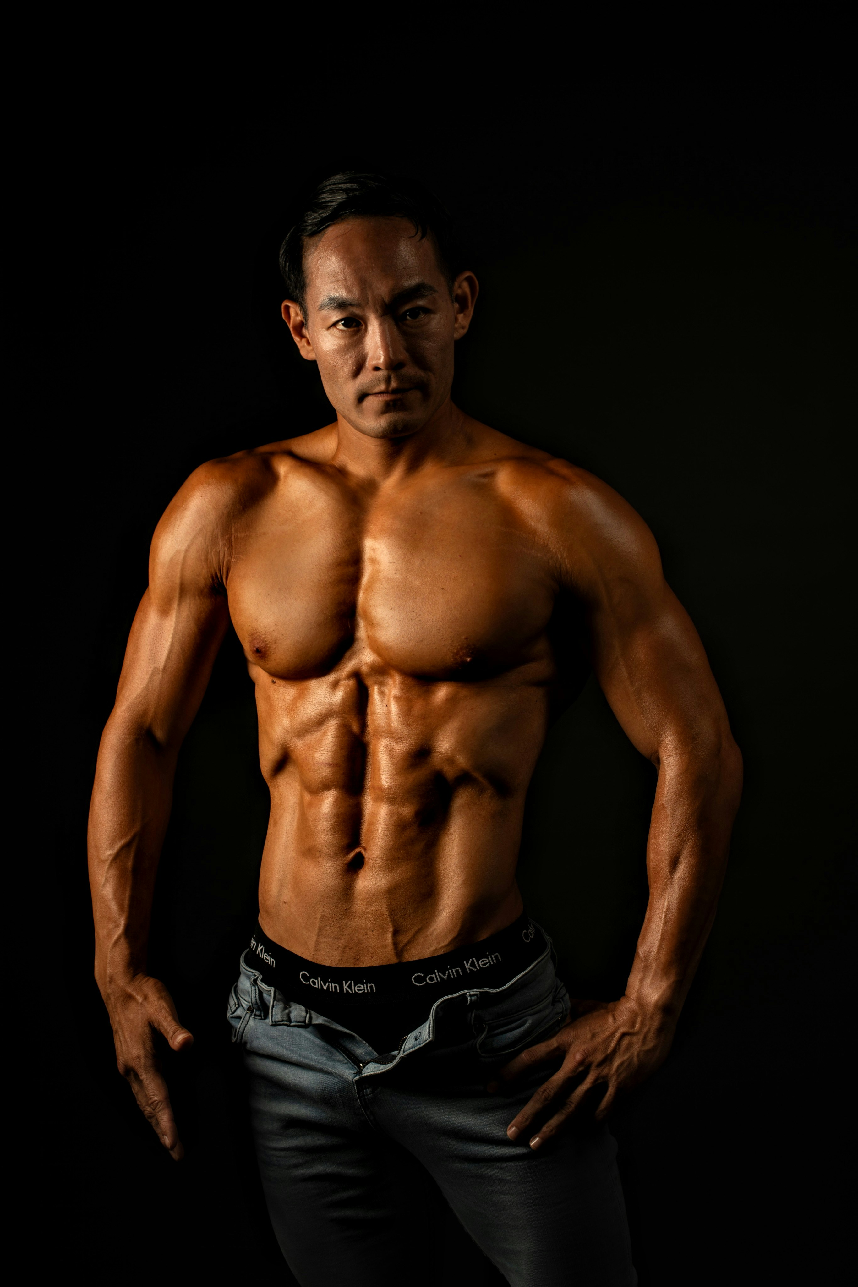 Muscular man posing shirtless against a black background.
