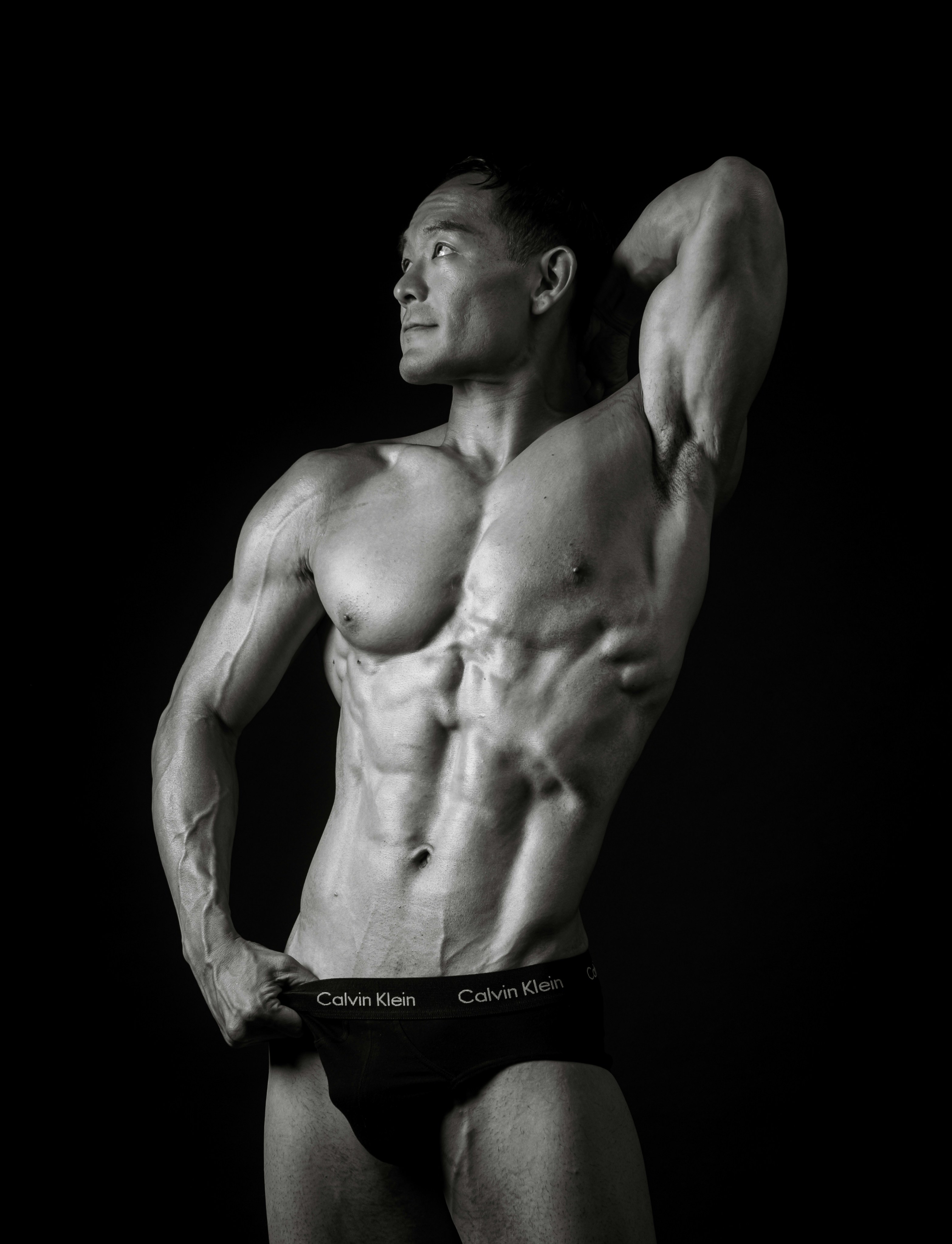 A muscular man poses against a black background.