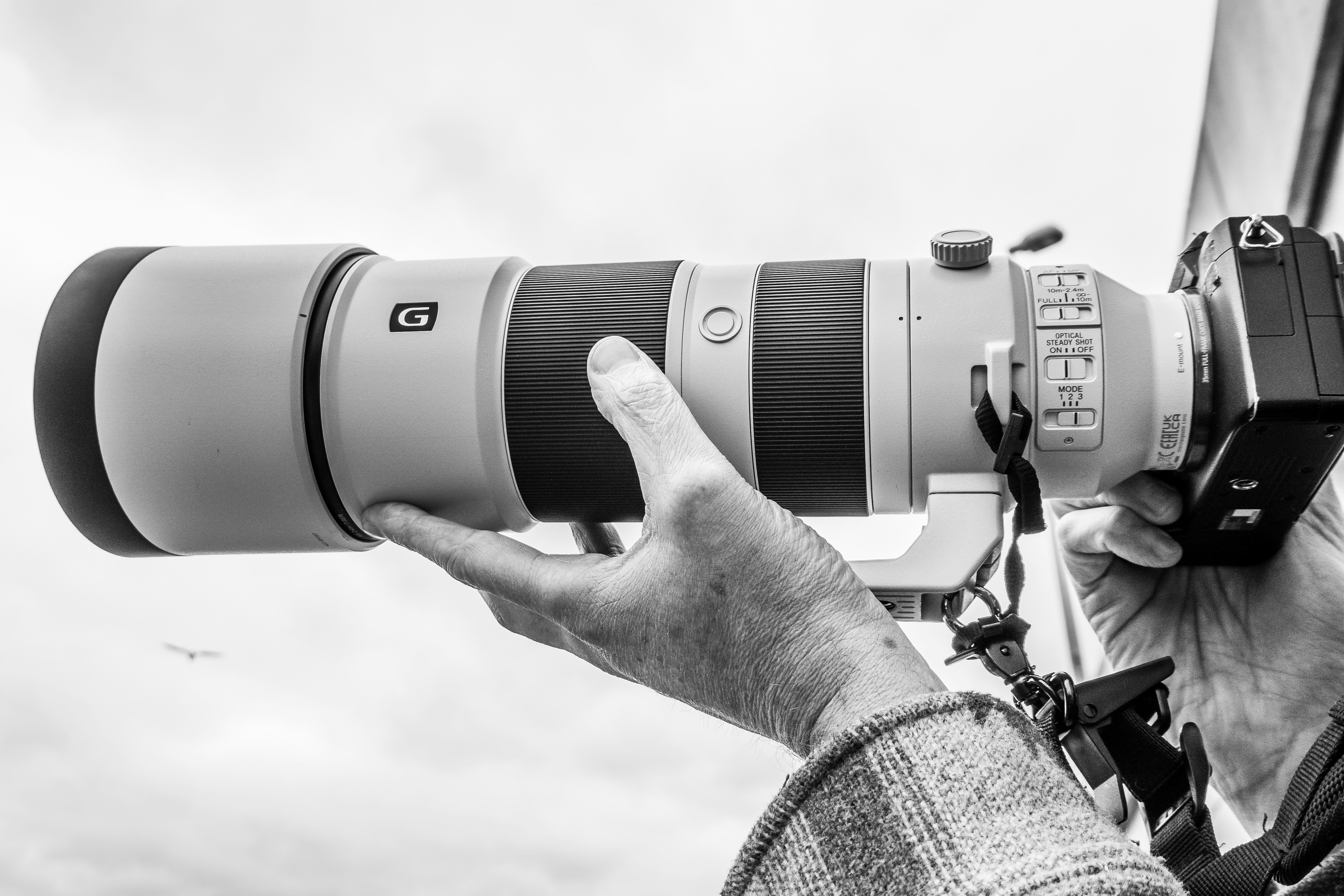 Photographer holds a camera with a large lens.