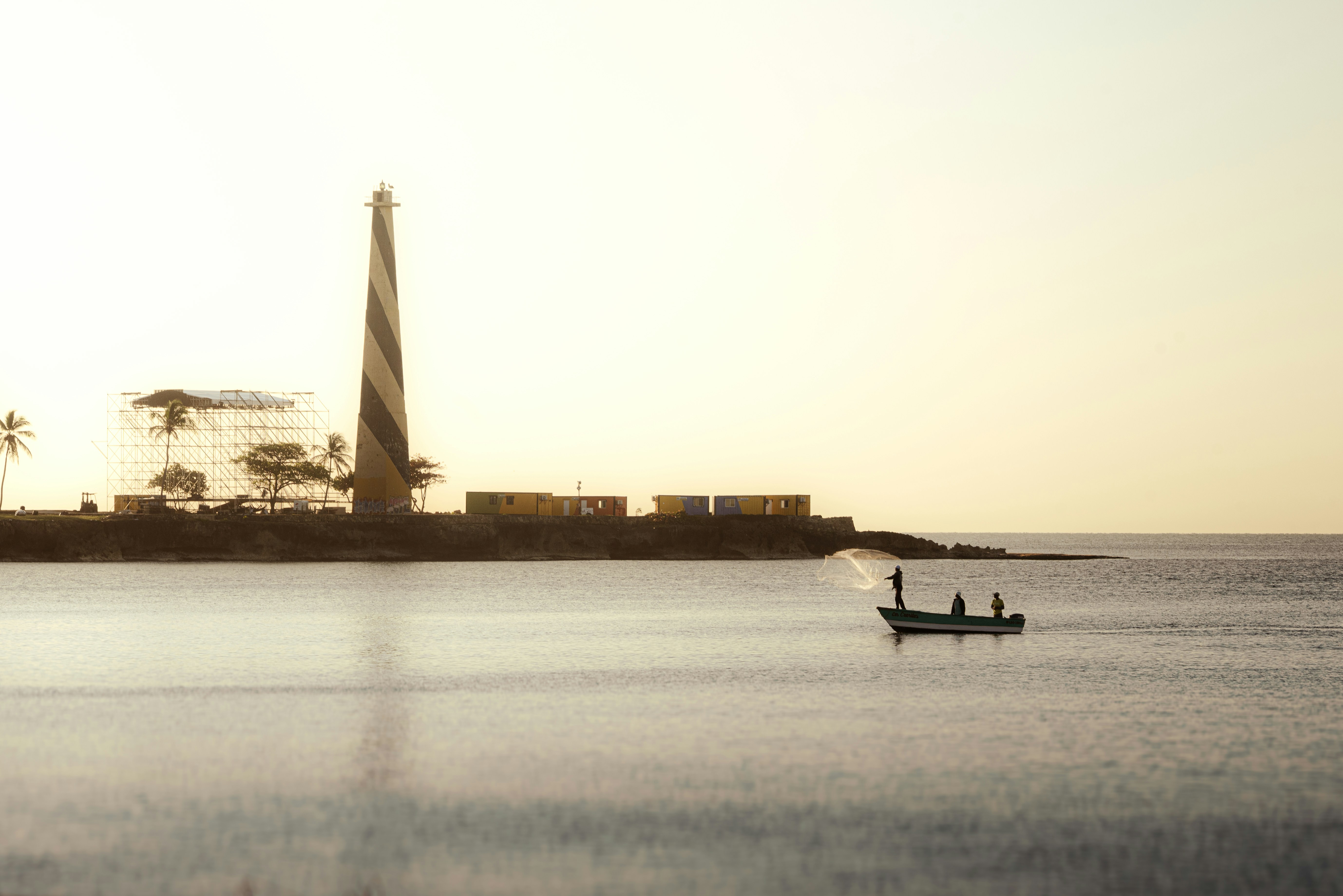 A lighthouse and a boat on a calm sea.