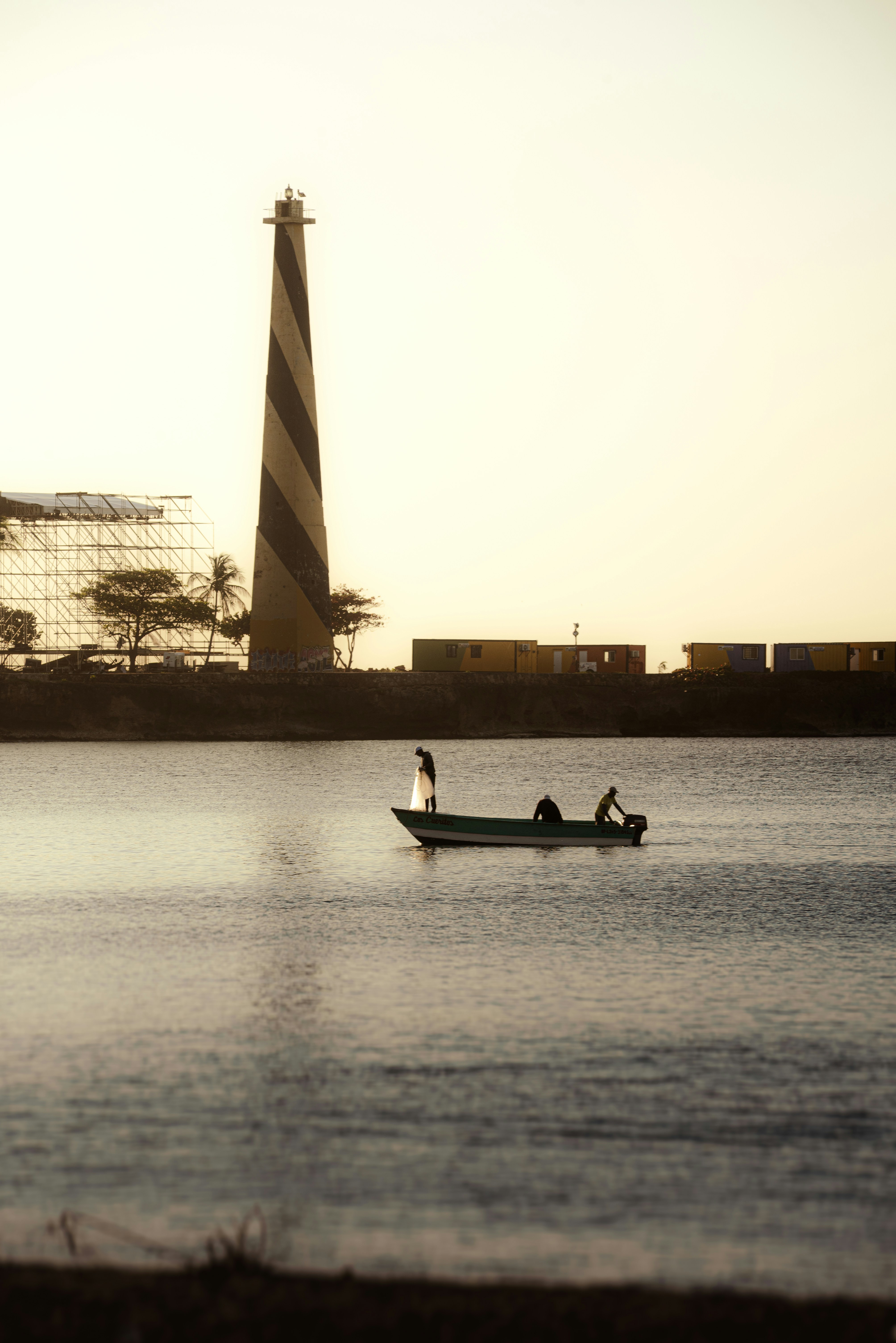 Boat travels near a lighthouse on the water.