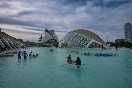 Boats float on the water near modern buildings.