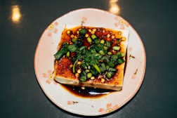 Tofu dish topped with greens and sauce.
