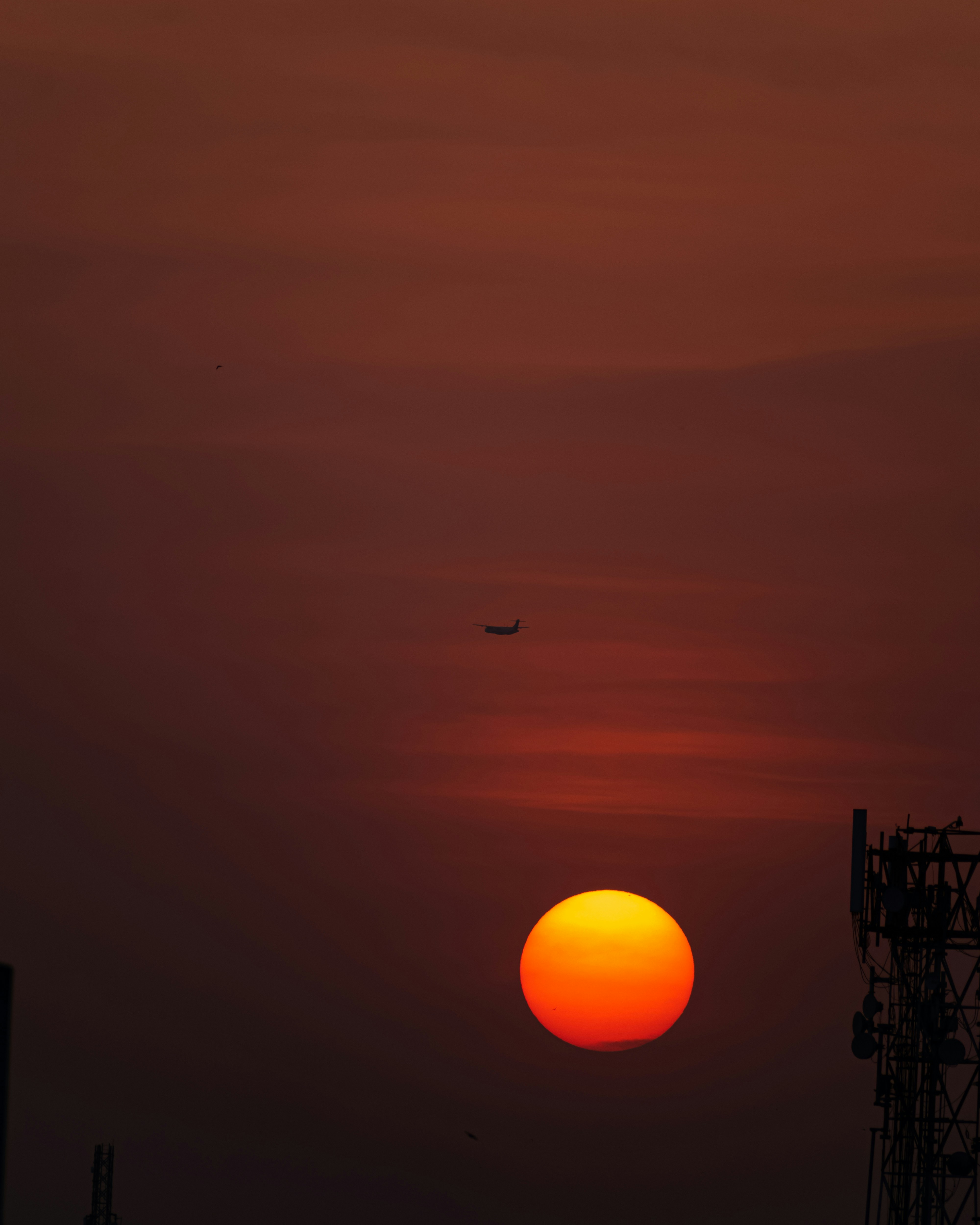 Sunset silhouettes an airplane and tower.