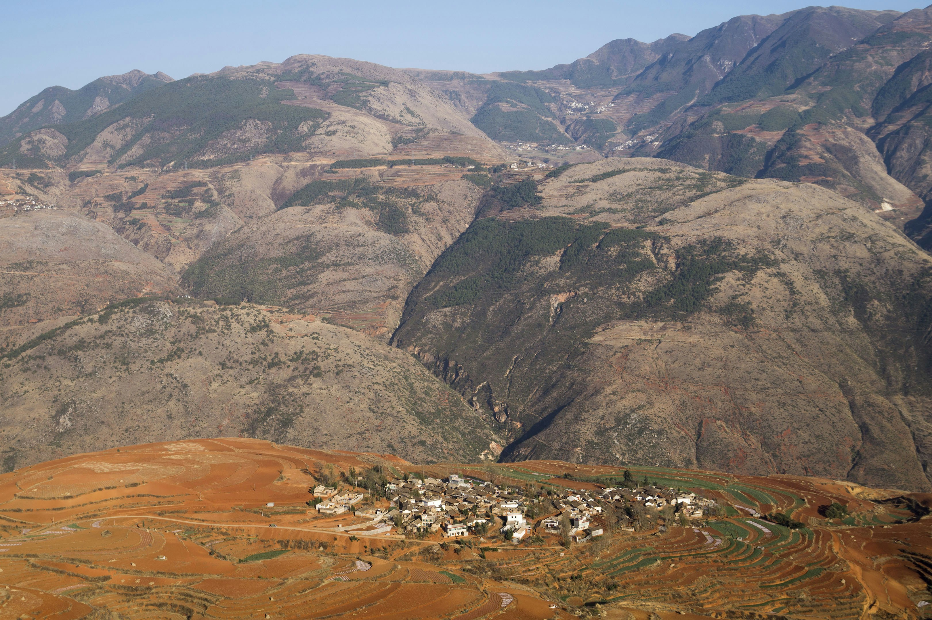 A village sits nestled among brown mountains.